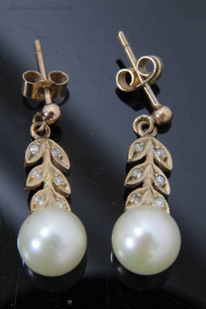 Lot 44 - Pair of cultured pearl and diamond pendant earrings with a 7mm cultured pearl suspended from stylized diamond foliage in 9ct gold setting. 21mm