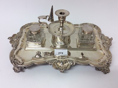 Lot 272 - Late Victorian silver plated double inkstand with cut glass bottles and central taper stick with snuffer, foliate scroll borders and four scroll feet, 33cm long x 23cm wide (to be sold on behalf of...