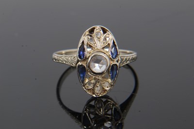 Lot 231 - Art Deco diamond and sapphire plaque ring with an oval openwork plaque with a central rose cut diamond, four pear cut blue sapphires (possibly synthetic) and rose cut diamonds, pierced gallery and...