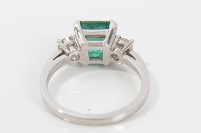Lot 237 - Emerald and diamond three stone ring with a square step-cut emerald measuring approximately 7.50mm x 7.25mm x 5.25mm, estimated to weigh approximately 1.90cts, flanked by two old cut diamonds in cl...