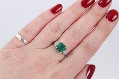 Lot 237 - Emerald and diamond three stone ring with a square step-cut emerald measuring approximately 7.50mm x 7.25mm x 5.25mm, estimated to weigh approximately 1.90cts, flanked by two old cut diamonds in cl...
