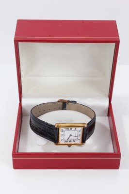 Lot 311 - Cartier Tank wristwatch, the white rectangular dial with black enamel Roman numerals and black hands, quartz movement in  silver gilt case with blue cabochon sapphire to the winding crown, on blue...