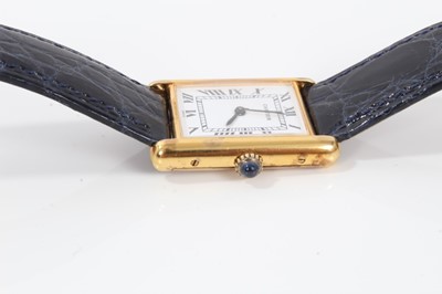 Lot 311 - Cartier Tank wristwatch, the white rectangular dial with black enamel Roman numerals and black hands, quartz movement in  silver gilt case with blue cabochon sapphire to the winding crown, on blue...