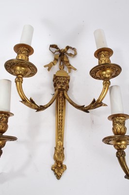 Lot 308 - Set of four brass two branch wall lights with ribbon and lion mask decoration