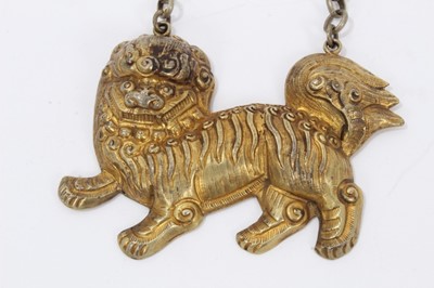Lot 4 - Old Chinese gilt metal panel necklace decorated with a figure riding a dragon, one other gilt metal figurative panel and a gilt metal dog of foo necklace