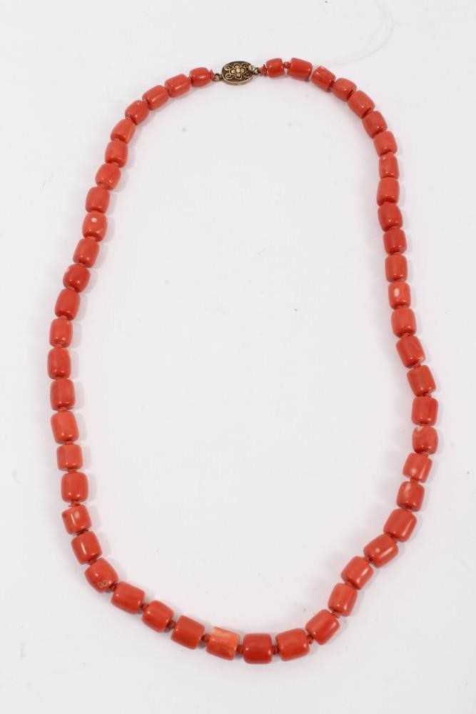 Lot 46 - Old Chinese coral necklace with barrel shaped polished beads and oval silver gilt clasp with wire work flower decoration, 63cm long