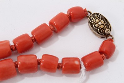 Lot 46 - Old Chinese coral necklace with barrel shaped polished beads and oval silver gilt clasp with wire work flower decoration, 63cm long