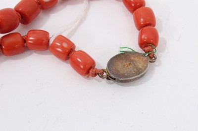 Lot 48 - Old Chinese coral necklace with barrel shaped polished beads and oval silver clasp with wire work flower decoration, 65cm long