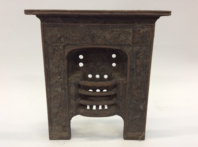 Lot 1895 - Three miniature Victorian ornamental cast iron fireplaces, a cast iron front plate, ash pan front and miniature front (6)