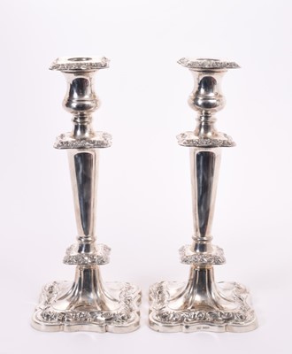 Lot 384 - Pair of silver Elizabeth II silver candlesticks of tapered form with urn shaped candle holders, removable sconces and scroll borders, on shaped square bases, (Sheffield 1964)