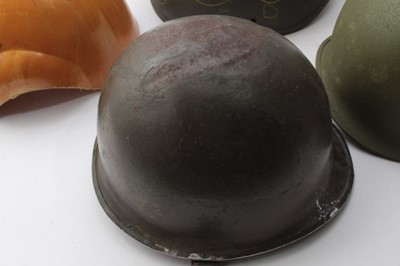 Lot 263 - American M1 Steel helmet reworked for the Korean War, together with another M1 steel helmet and two helmet shells (4)
