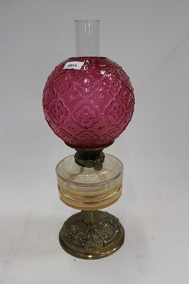 Lot 2013 - Edwardian oil lamp with cranberry glass shade, cut glass reservoir on embossed brass base