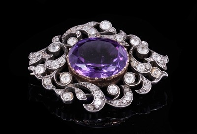 Lot 353 - Late Victorian amethyst and diamond brooch with a central oval mixed cut amethyst measuring approximately 16mm x 13.5mm with old cut diamonds in openwork foliate scrolls with silver and gold settin...