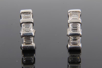 Lot 397 - Pair of diamond earrings, each curved band with six baguette cut diamonds in 9ct white gold setting. 15mm