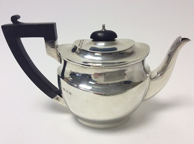 Lot 156 - George V silver teapot of oval form, domed hinged cover with ebony knop and angular ebonised handle, (London 1920), maker George Unite, 22cm from handle to spout, all at approximately 15oz