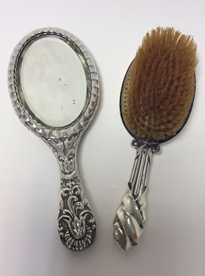 Lot 159 - Victorian silver backed hand mirror with ornate embossed decoration (Birmingham 1876), together with three silver backed brushes and two silver silver topped
