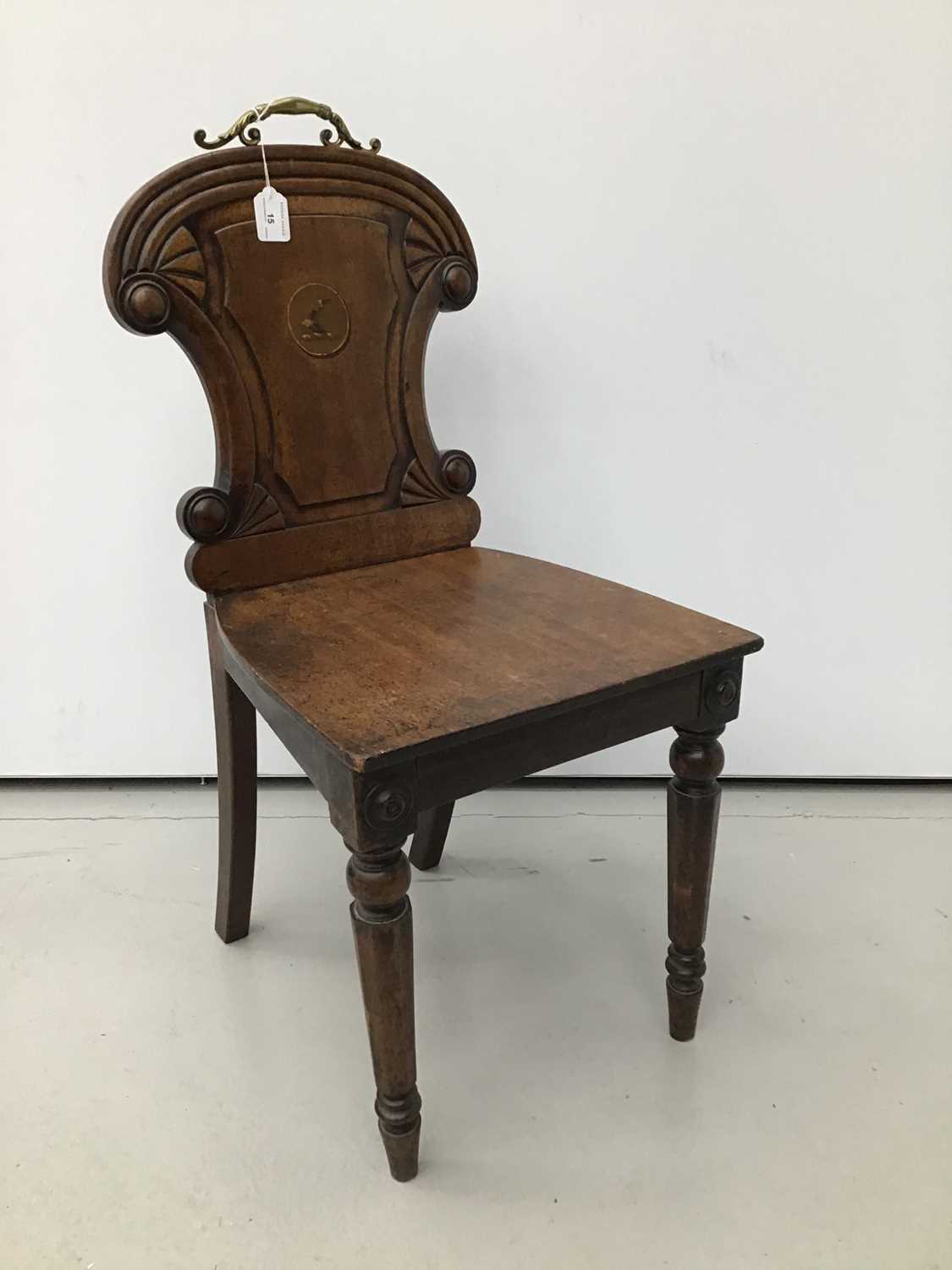 Lot 15 - Regency mahogany hall chair, the arched panel back centred by recessed circular painted armorial crest roundel and solid seat on facetted legs, restorations