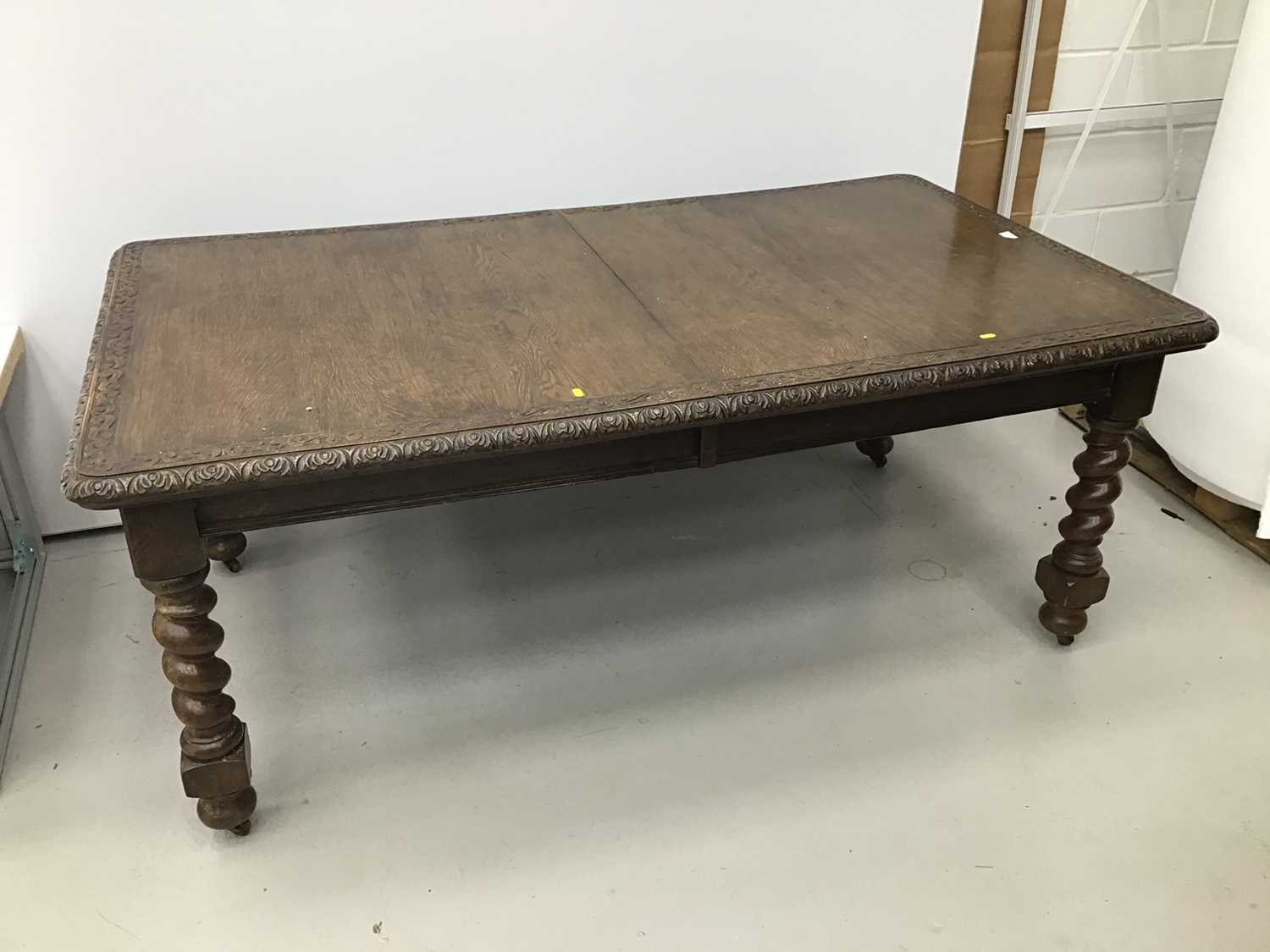 Lot 86 - Early 20th century oak extending dining table, the rounded rectangular wind out top with relief carved scroll border on barley twist legs abc castors, with two additional leaves 180 x 105cm extendi...