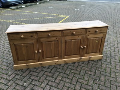 Lot 141 - Pine sideboard with four drawers and cupboards below enclosed by four panelled doors on plinth base, 214cm wide x 89cm high x 46cm deep
