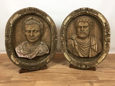 Lot 407 - Pair of 20th century highly decorative carved wooden oval roundels depicting portrait busts of Roman Emperors, on display stands