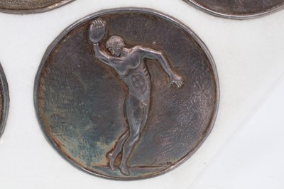 Lot 982 - Five silver Greek roundels, by Antigone Filippaki each circular embossed disc representing athletic disciplines, stamped marks and numbered .999, 10cm diameter, in marble frame mount