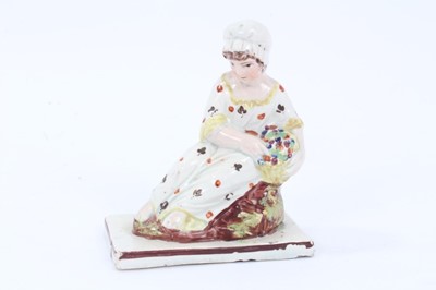 Lot 71 - Four Staffordshire pearlware figures, c.1800, including two reclining figures, possibly representing seasons, a kneeling woman, and a woman carrying a chicken, all with red-lined square bases, betw...
