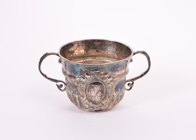 Lot 379 - A William and Mary Britannia silver porringer of conventional form, with engraved armorial crest and crown, twin scroll handles, fluted and fish scale decoration and ropework border, (London 1701)
