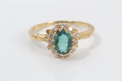 Lot 255 - Emerald and diamond cluster ring with an oval mixed cut emerald estimated to weigh approximately 0.87cts surrounded by a border of twelve brilliant cut diamonds in gold claw setting with scroll sho...
