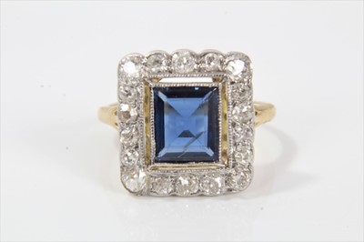 Lot 318 - Edwardian style sapphire and diamond cluster ring with a rectangular step cut blue sapphire estimated to weigh approximately 1.24cts in openwork mille grain setting with a border of 18 old cut diam...