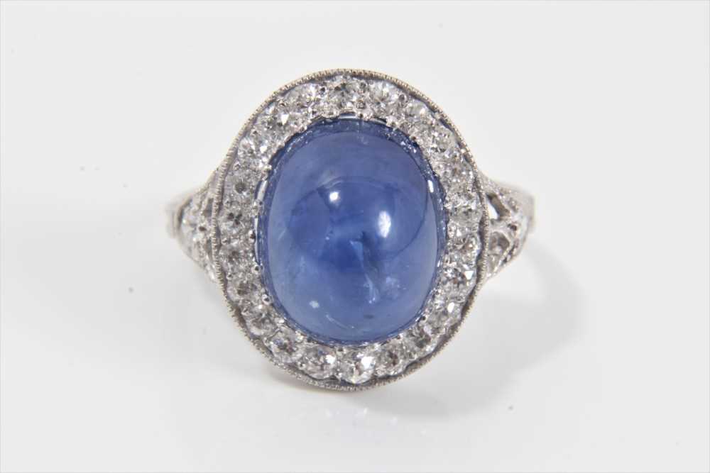 Lot 319 - Edwardian style sapphire and diamond cluster ring with an oval cabochon blue sapphire weighing approximately 8.49cts surrounded by a border of old cut diamonds in millegrain setting with pierced ga...