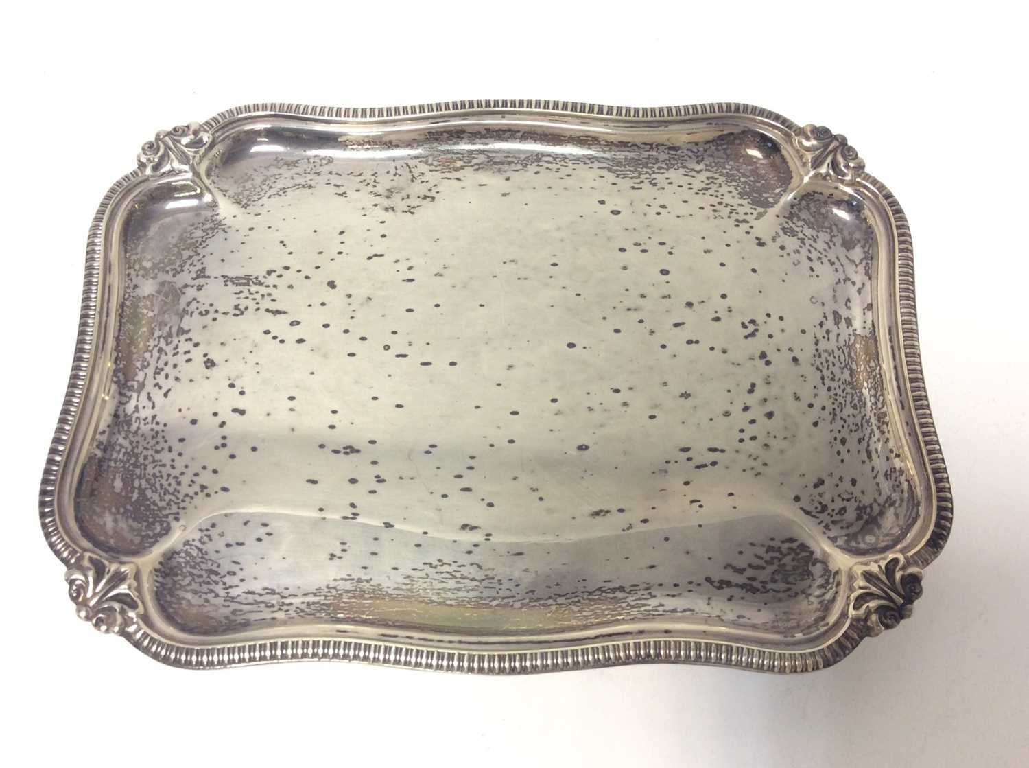 Lot 183 - George V silver waiter of rectangular form with gadrooned and scroll borders, raised on four scroll feet, (Sheffield 1926), maker Harrison Brothers & Howson, all at approximately 13oz, 20cm in leng...
