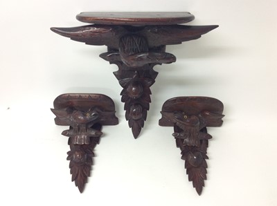 Lot 419 - Garniture of three late 19th century Black Forest carved wooden wall brackets with eagle