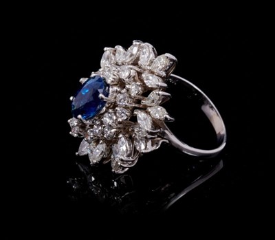 Lot 245 - Sapphire and diamond cluster cocktail ring with an oval mixed cut blue sapphire estimated to weigh approximately 1.75cts surrounded by 18 brilliant cut and 24 marquise cut diamonds in tiered claw s...