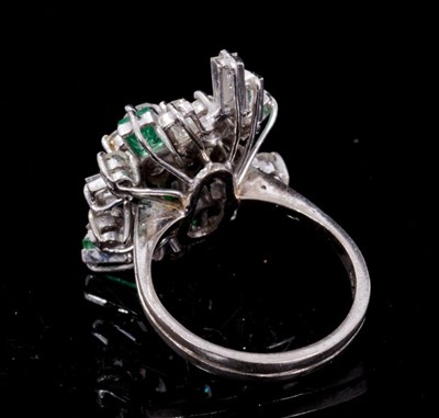 Lot 252 - Emerald and diamond cluster cocktail ring with an asymmetrical cluster of brilliant cut an baguette cut diamonds, and rectangular step cut emeralds, all in tiered claw setting on 18ct white gold sh...