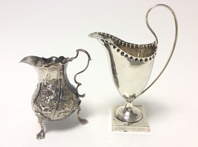Lot 187 - George III silver cream jug of baluster form, raised on three hoof feet, (London 1764), together with a Victorian silver cream jug of helmet form, (Birmingham 1876), Georgian cream jug 9.8cm  in he...