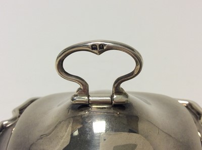 Lot 190 - George V silver tea caddy of cauldron form with twin ring handles, hinged cover with folding handle and gilded interior, raised on four hoof feet, (London 1917), maker Goldsmiths & Silversmiths Com...