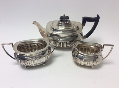 Lot 198 - Edwardian silver three piece teaset comprising teapot of cauldron form with fluted decoration, domed hinged cover with ebony finial and angular ebony handle, on four bun feet, together with matchin...