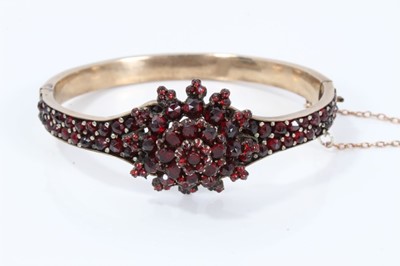 Lot 306 - Late 19th century Bohemian garnet hinged bangle with a flower head cluster on pavé set band in gilt metal setting.