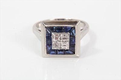 Lot 278 - Diamond and sapphire cluster ring with a square cluster of four invisibly set square cut diamonds surrounded by a border of calibre cut blue sapphires with bevelled platinum square bezel, pierced g...