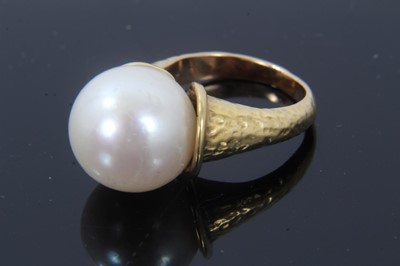 Lot 291 - Cultured pearl ring with a large single cultured pearl measuring approximately 12.8mm diameter in gold setting of organic modernist form with hammered finish. Signed 'Bagge', probably Eric Bagge (1...