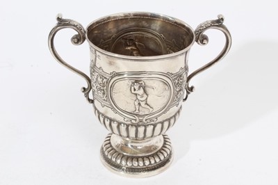 Lot 300 - George V Scottish silver two handled trophy cup of conventional form with fluted decoration, embossed scenes depicting a Golfer, two scroll handles with acanthus leaf terminals, raised on circular...