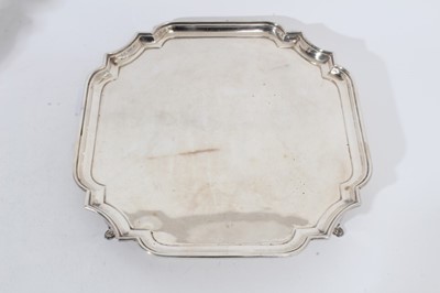 Lot 258 - George V silver salver of square form, with pie crust decoration to corners, raised on four hoof feet (Birmingham 1913), maker Barker Brothers Silver Ltd, all at approximately 40oz, 31cm in diamete...