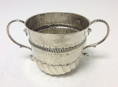 Lot 136 - A William and Mary Britannia silver porringer of conventional form, with engraved armorial crest and crown, twin scroll handles, fluted and fish scale decoration and ropework border, (London 1701)