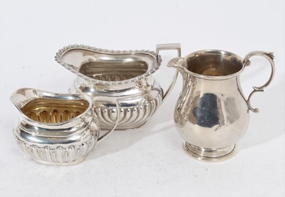 Lot 267 - Edwardian silver milk / cream jug of baluster form with scroll handle, (London 1907), together with a Victorian silver cream jug of cauldron form with fluted decoration, (Birmingham 1900) and anoth...