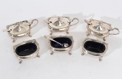 Lot 272 - Three Elizabeth II silver mustard pots of cauldron form with gadrooned borders, domed hinged covers and blue glass liners, raised on four paw feet, together with three matching salt cellars, (Birmi...