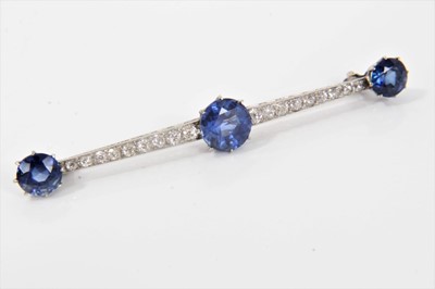 Lot 335 - Edwardian diamond and blue stone bar brooch the a line of 18 graduated old cut diamonds interspaced by three round mixed cut blue stones, 62mm length, in an associated Garrard box.