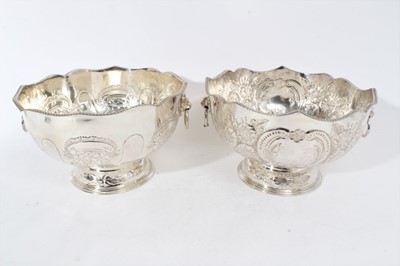 Lot 291 - Pair of 20th Century silver plated punch bowls with embossed decoration, twin Lion mask handles and gadrooned borders, raised on circular feet, each 20cm in height (2)