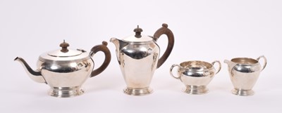 Lot 370 - George V silver teapot of cauldron form, with reeded border, carved wood loop handle and domed hinged domed cover on a circular foot, together with matching hot water pot