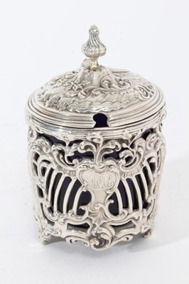 Lot 381 - Late 19th century silver mustard pot of cylindrical form with ornate pierced rococo scroll decoration, hinged cover with blue glass liner