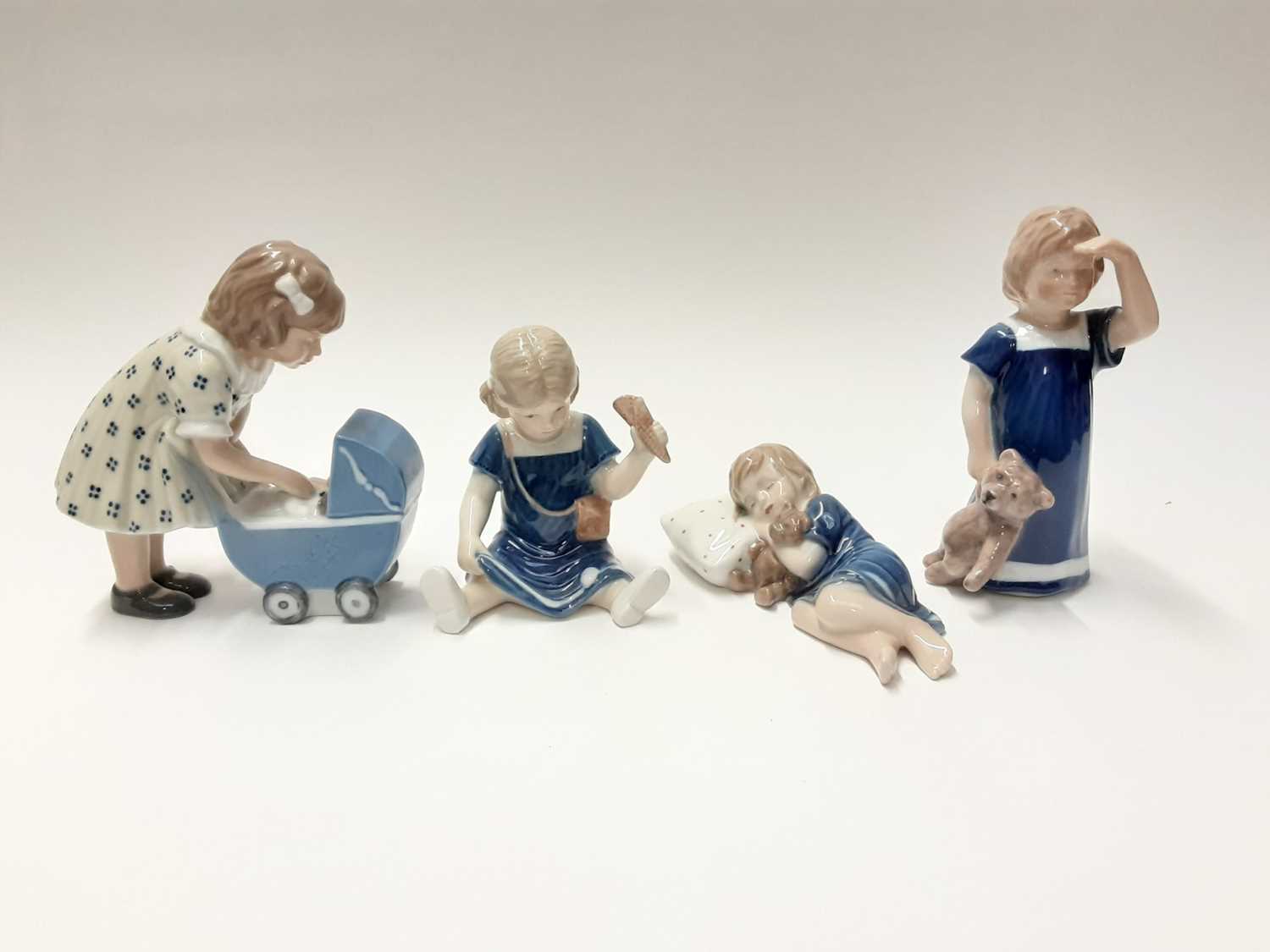 Lot 150 - Four Royal Copenhagen porcelain figures including girl with pram and girl with Teddy bear, model numbers 675, 673, 676 and 407